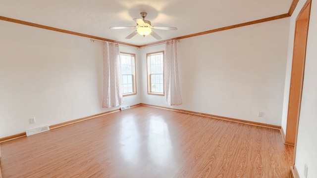 spare room featuring visible vents, a ceiling fan, wood finished floors, crown molding, and baseboards