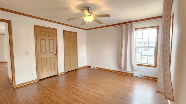 unfurnished bedroom with visible vents, ornamental molding, baseboards, and wood finished floors