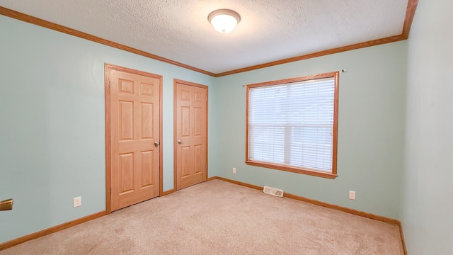 unfurnished bedroom featuring ornamental molding, baseboards, visible vents, and a textured ceiling