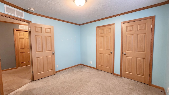 unfurnished bedroom with baseboards, visible vents, ornamental molding, a textured ceiling, and carpet flooring