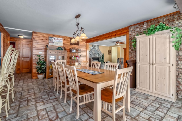 dining space with a fireplace and wooden walls