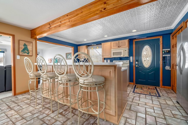 kitchen featuring crown molding, stainless steel fridge, range, and a breakfast bar area