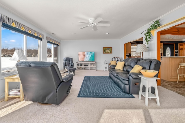 carpeted living room with ornamental molding and ceiling fan