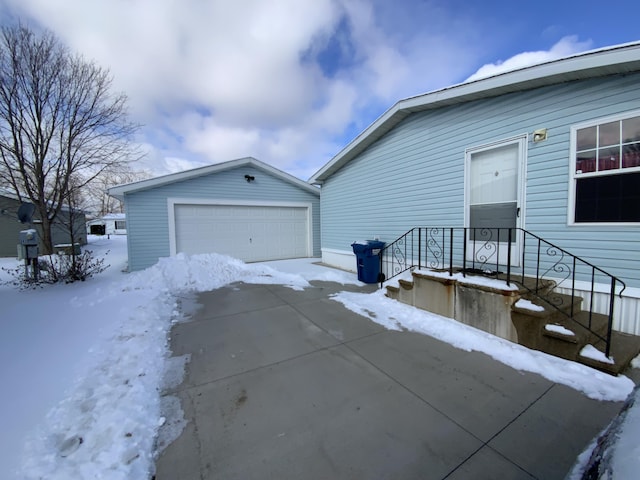 view of snow covered exterior featuring an outbuilding and a garage