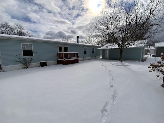 snow covered back of property with cooling unit and a deck