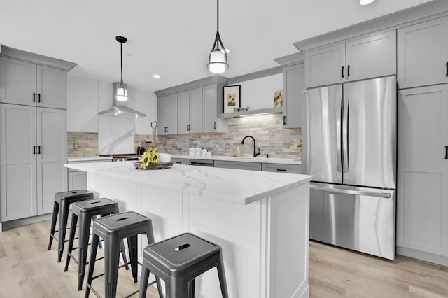 kitchen featuring a sink, stainless steel refrigerator, and gray cabinetry