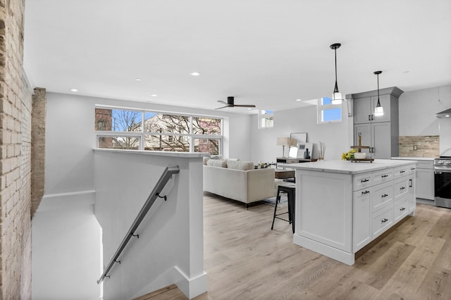 kitchen with a breakfast bar area, light wood-style flooring, stainless steel electric range, a center island, and tasteful backsplash