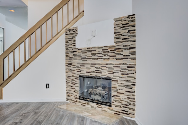 unfurnished living room featuring a tile fireplace and wood-type flooring