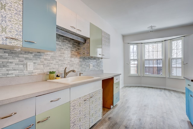 kitchen featuring sink, tasteful backsplash, and light hardwood / wood-style flooring