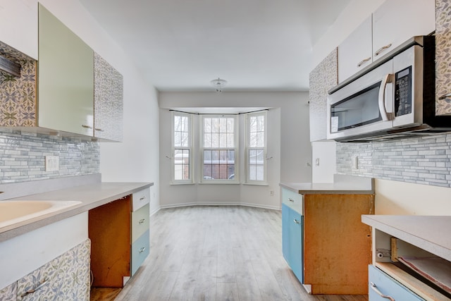 kitchen with light wood-type flooring, white cabinets, and decorative backsplash