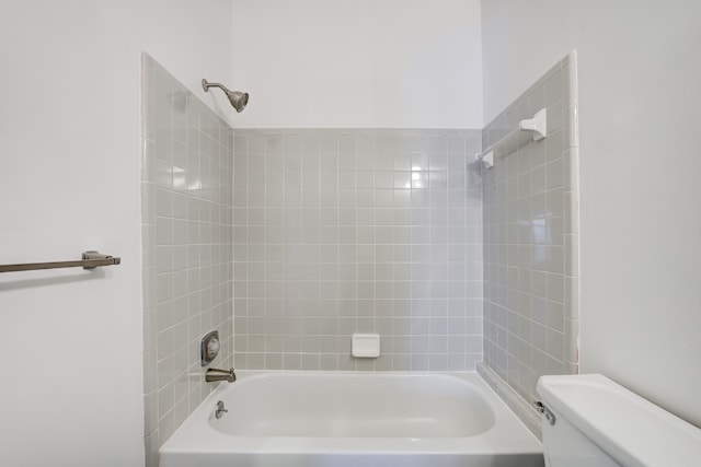 bathroom with tiled shower / bath combo and toilet