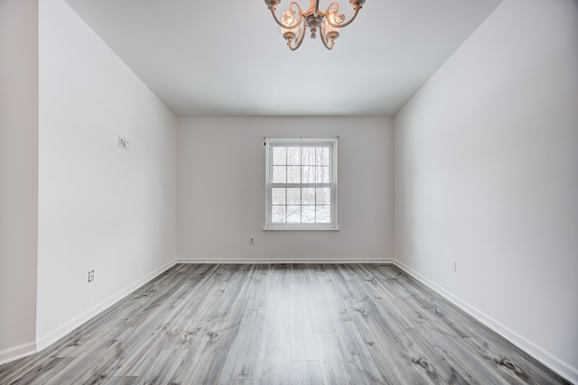 spare room with light hardwood / wood-style floors and an inviting chandelier