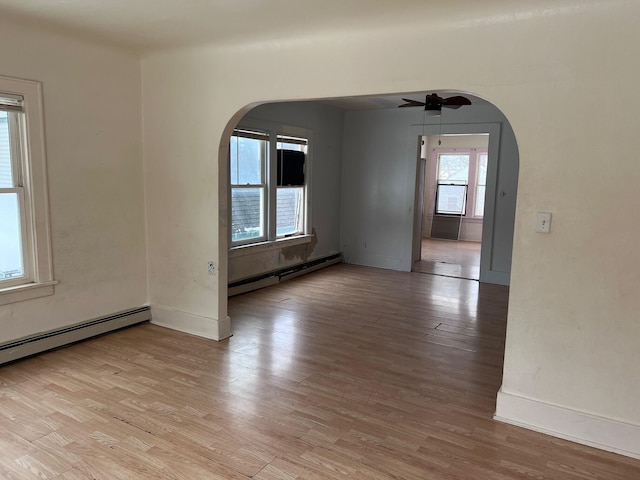 empty room featuring a baseboard heating unit, light hardwood / wood-style floors, and ceiling fan