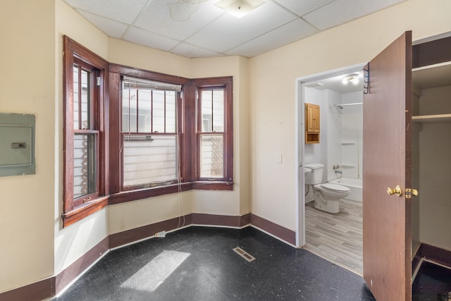 interior space featuring tile patterned floors, visible vents, electric panel, a drop ceiling, and baseboards