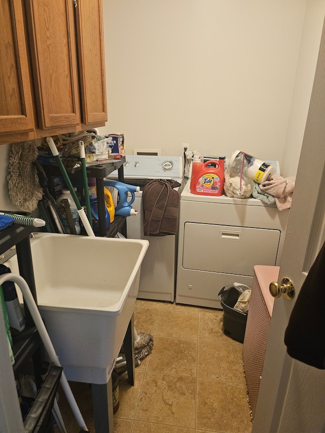 clothes washing area with light tile patterned flooring, cabinets, and separate washer and dryer