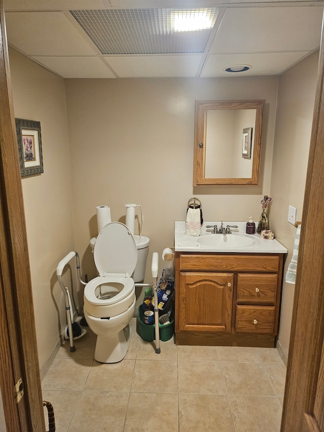 bathroom featuring toilet, vanity, tile patterned flooring, and a drop ceiling