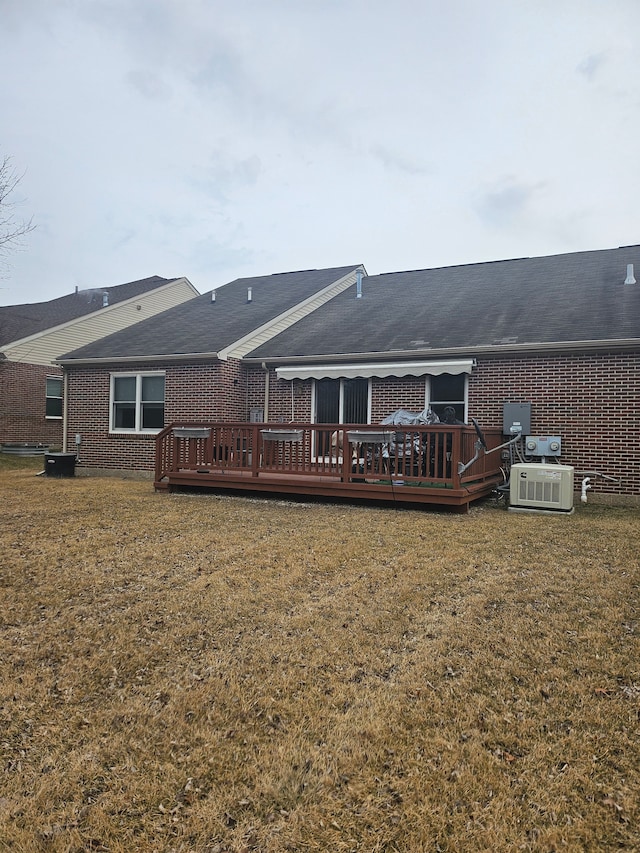 rear view of house featuring central air condition unit, a deck, and a lawn