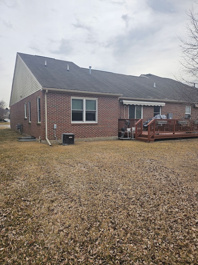 rear view of property featuring a yard, cooling unit, and a wooden deck