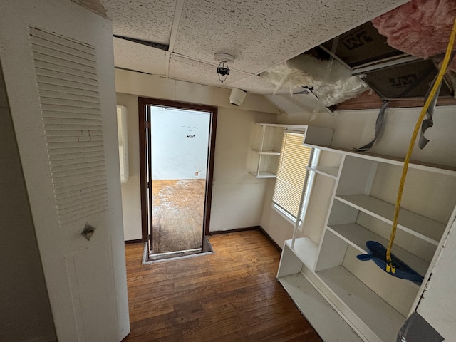 corridor featuring wood-type flooring and baseboards