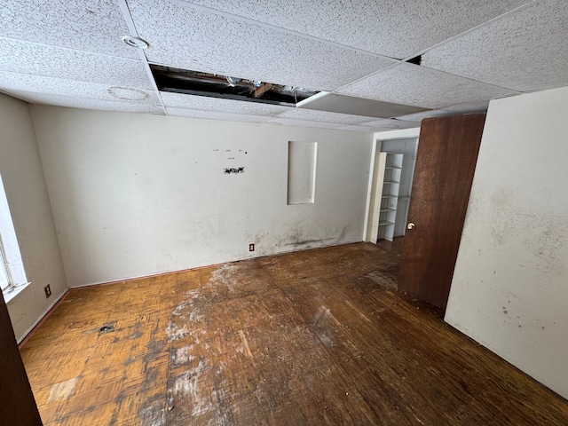 spare room with dark wood-type flooring and a drop ceiling