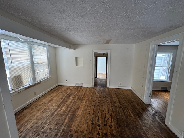 spare room featuring visible vents, dark wood finished floors, a textured ceiling, and baseboards