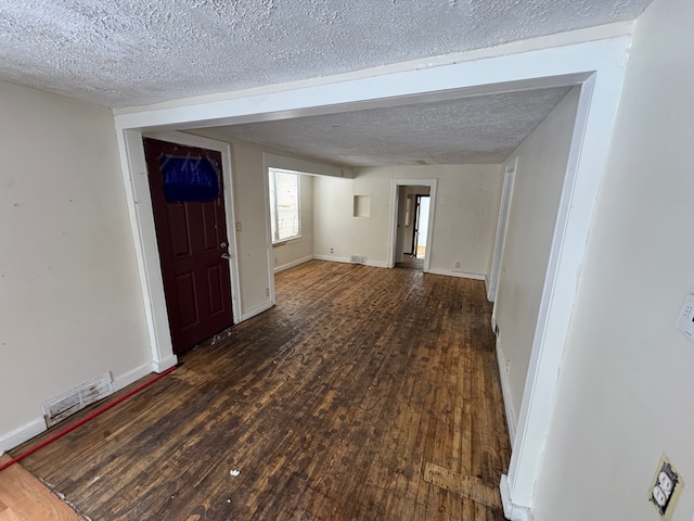 interior space featuring dark wood-style floors, baseboards, visible vents, and a textured ceiling