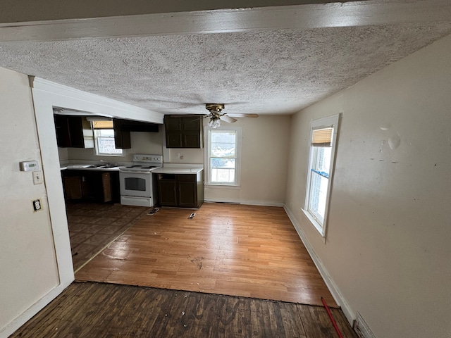 kitchen featuring baseboards, light countertops, dark brown cabinets, white range with electric stovetop, and wood-type flooring