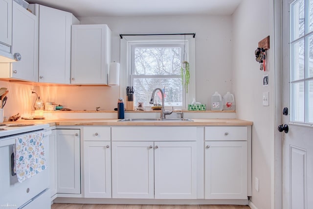 kitchen with white cabinetry, plenty of natural light, sink, and electric range