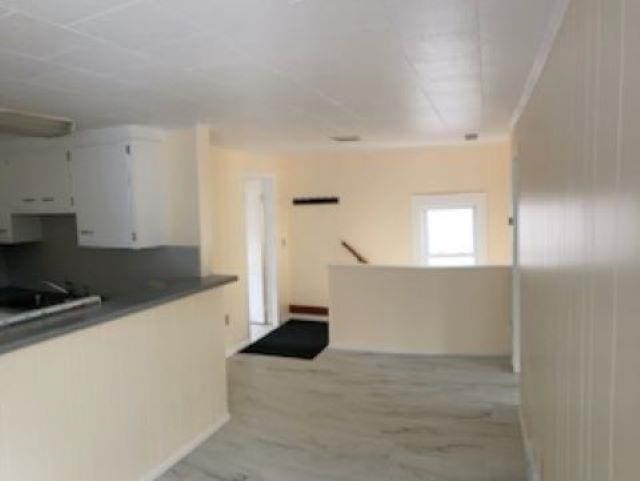 kitchen featuring light wood-type flooring, dark countertops, and white cabinets