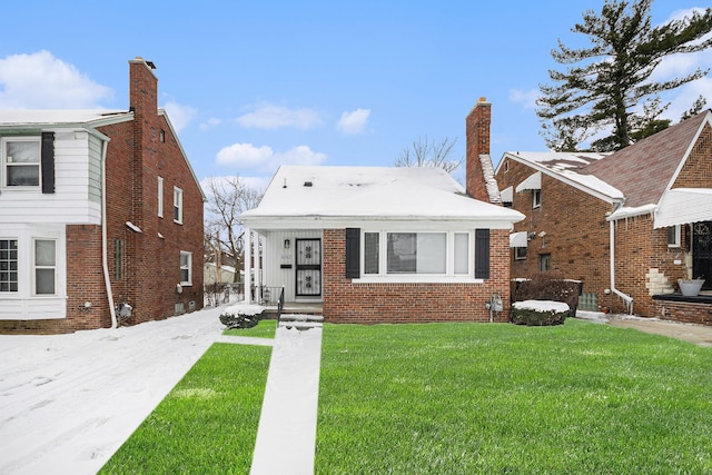 bungalow-style home featuring brick siding, a chimney, and a front yard