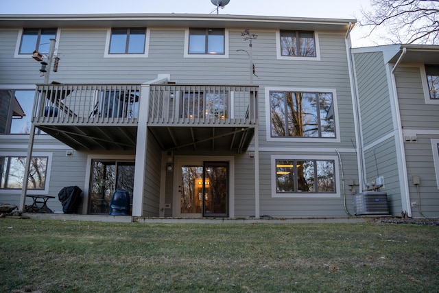 back of house featuring central AC, a wooden deck, and a lawn