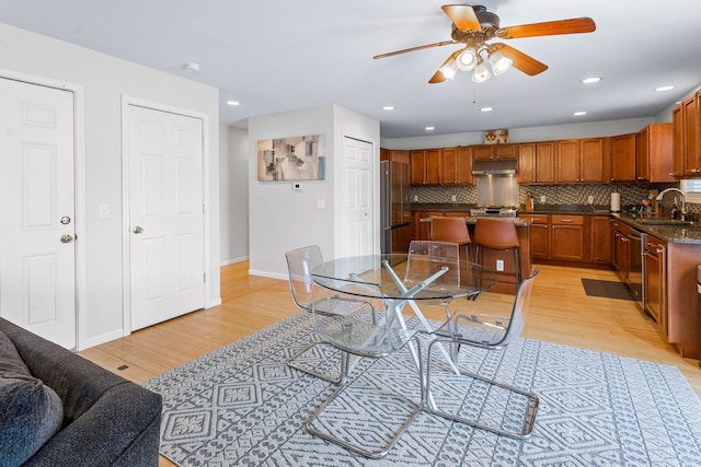 dining room with sink, light wood-type flooring, and ceiling fan