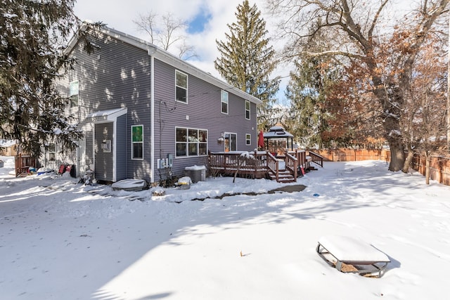 snow covered house featuring cooling unit and a wooden deck