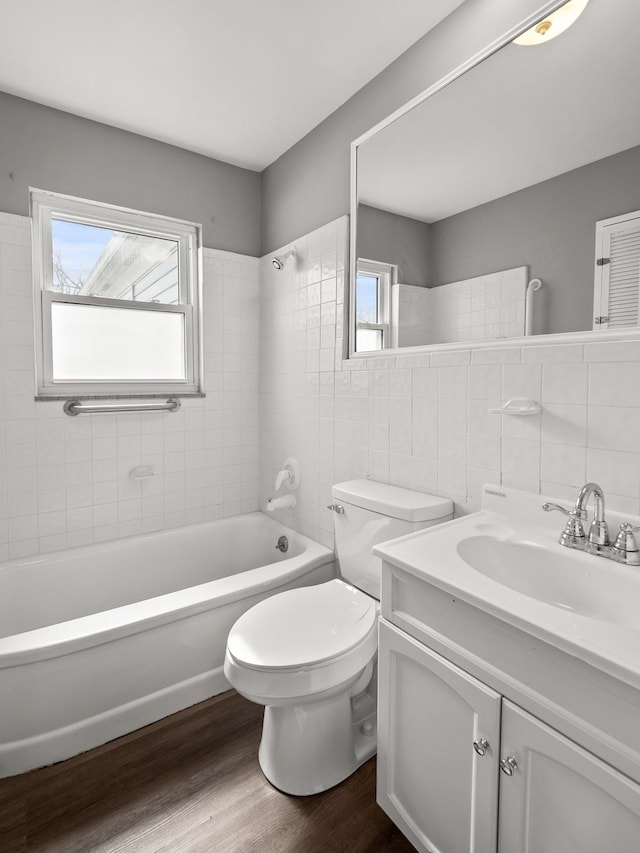 full bathroom with wood-type flooring, tile walls, tiled shower / bath combo, vanity, and toilet