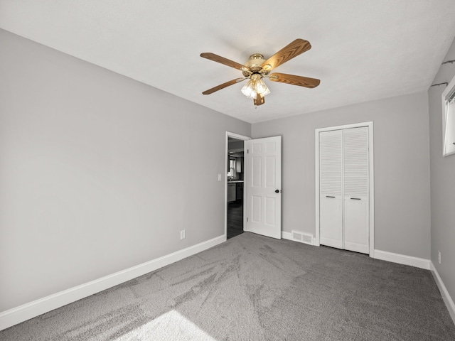 unfurnished bedroom with dark colored carpet, ceiling fan, and a closet