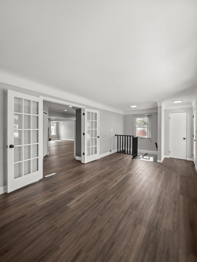 unfurnished living room with dark hardwood / wood-style flooring and french doors