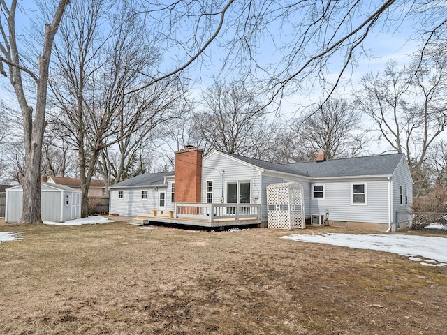 back of house with a wooden deck, a shed, and a lawn