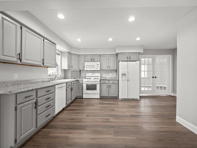 kitchen featuring gray cabinets, dark hardwood / wood-style floors, sink, light stone countertops, and white appliances