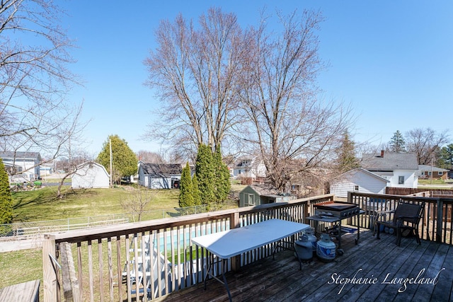 deck with a residential view, a fenced backyard, a lawn, an outdoor structure, and a shed