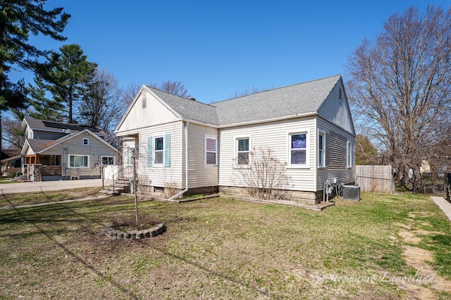 exterior space featuring fence, a shingled roof, a front yard, and central air condition unit