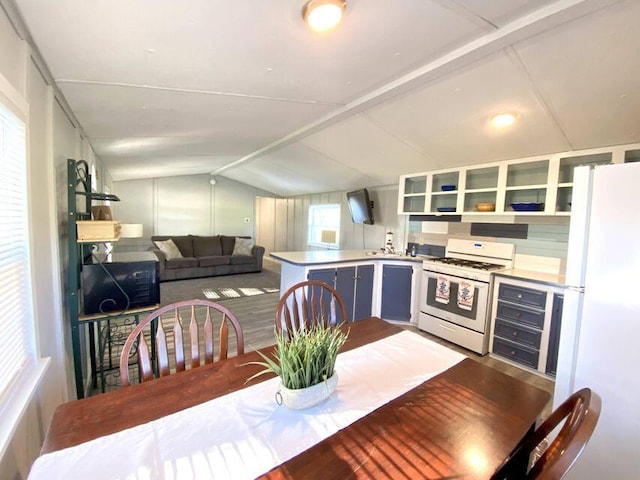 kitchen featuring vaulted ceiling, white appliances, and kitchen peninsula