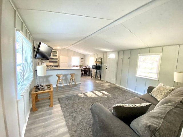 living room featuring a healthy amount of sunlight, wood-type flooring, and lofted ceiling with beams