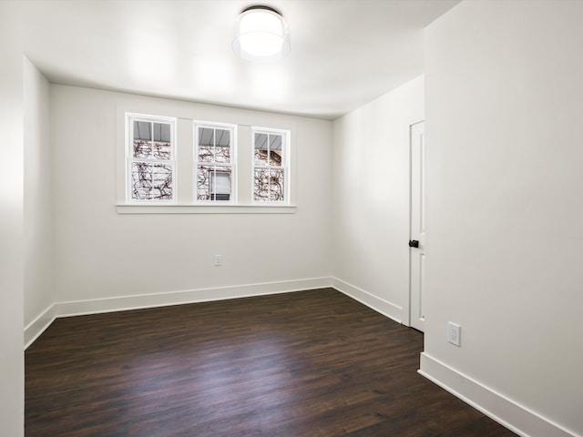 unfurnished room with dark wood finished floors and baseboards