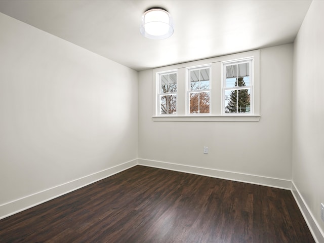 empty room with baseboards and dark wood-type flooring