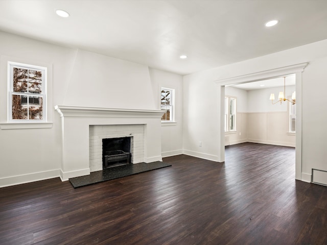 unfurnished living room with baseboards, dark wood-style flooring, a brick fireplace, and recessed lighting