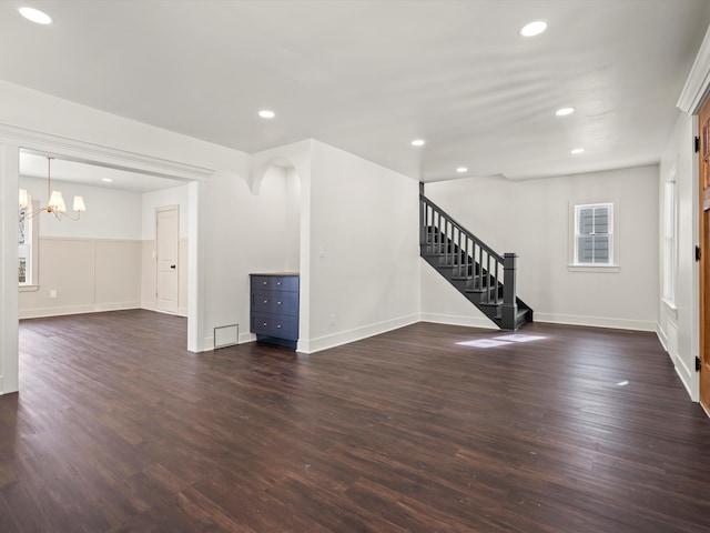 unfurnished living room featuring recessed lighting, dark wood finished floors, and stairs