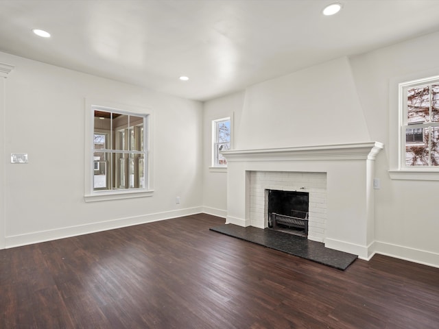 unfurnished living room with a healthy amount of sunlight, a fireplace, and dark wood-type flooring