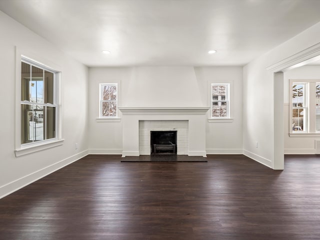 unfurnished living room with a fireplace with raised hearth, dark wood-style flooring, recessed lighting, and baseboards