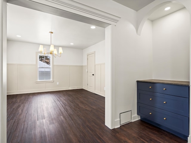 interior space featuring arched walkways, wainscoting, dark wood-style floors, a notable chandelier, and recessed lighting