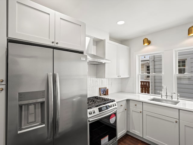 kitchen featuring decorative backsplash, wall chimney exhaust hood, appliances with stainless steel finishes, light countertops, and a sink